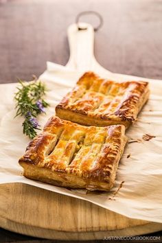 two square pastries sitting on top of a wooden cutting board