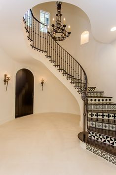 an elegant staircase with chandelier and tiled floor