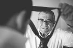 an older man wearing glasses and a neck tie looking at his reflection in the mirror