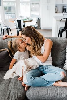 a mother kissing her two daughters on the couch