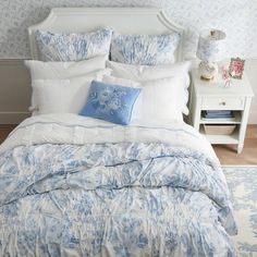 a bed with blue and white comforters in a bedroom next to a night stand