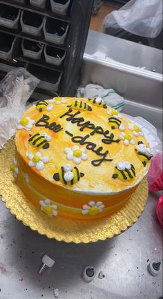 a birthday cake with yellow frosting and bees on it sitting on top of a table