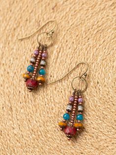 the beaded earrings are hanging from hooks on a piece of woven material, which has been