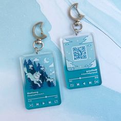 there are two keychains with an image of a wolf on them, one is blue and the other is white