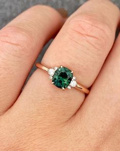 a woman's hand with a green and white diamond ring on her left hand