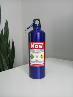 a blue water bottle sitting on top of a white table next to a green plant