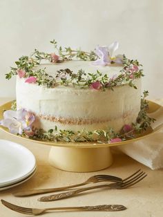 a cake with flowers on it sitting on a plate next to a fork and knife