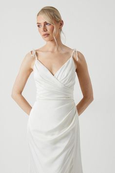 a woman is wearing a white dress with one shoulder and straps on the back,