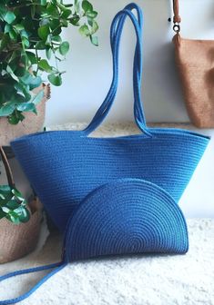 a blue purse sitting on top of a white rug next to a potted plant