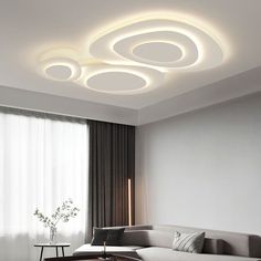 a modern living room with white furniture and round lights on the ceiling above the couch