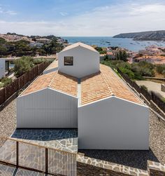 an aerial view of the roof of a building with water in the background and hills to the side