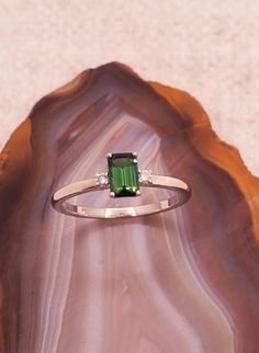 a green ring sitting on top of a piece of wood next to a stone slab