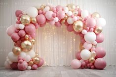 a pink and gold balloon arch with balloons