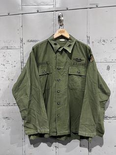 60's OG-107 Fatigue Button Up Shirt- Vietnam War(Army Green)  Great vintage condition. See pictures for condition Medium . Please review measurements as some vintage items fit smaller than modern sizing. Measurements taken with garment laid flat: 23" across from armpit to armpit 28" length from shoulder to hem 23.5" sleeve from shoulder to hem Please send a message if you have any questions. Double check measurements and inspect all pictures carefully before purchasing. Orders ship via USPS. All Military Style Collared Top With Snap Buttons, Vintage Green Button-up Shirt, Vintage Outerwear With Pockets And Short Sleeves, Vintage Khaki Tops With Snap Buttons, Retro Khaki Button-up Shirt, Vintage Khaki Button-up Top, Vintage Collared Khaki Tops, Vintage Khaki Collared Tops, Vintage Khaki Top With Pockets