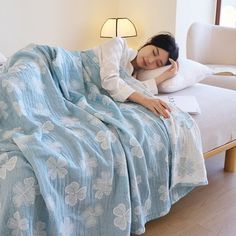 a woman laying on top of a bed under a blue blanket