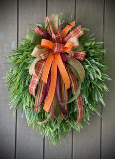 a wreath with orange and green ribbons hanging on a wall