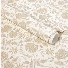 a white and beige wallpaper with floral design on the bottom, along with a roll of tape