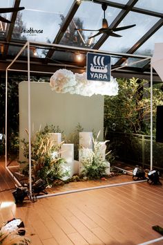 a room filled with lots of white flowers and plants under a glass roof covered area