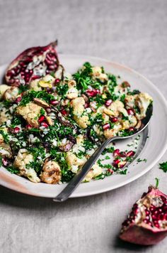 a white plate topped with food next to a cut in half pomegranate