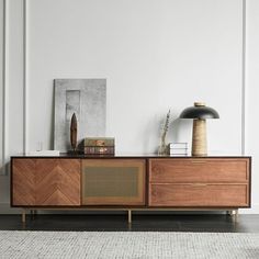 a sideboard with two drawers and a lamp on top in a white walled room