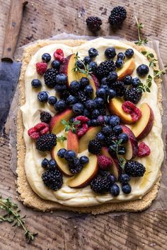 an uncooked pastry with fruit on it and some herbs next to the crust