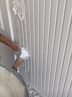 a person is painting the wall with white paint