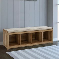 a wooden bench sitting in front of a window next to a rug on the floor