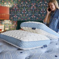 a woman is talking on her cell phone while laying in bed with two mattresses