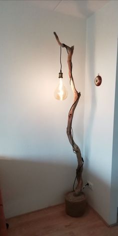 a lamp that is on top of a wooden stand next to a wall with a light bulb hanging from it