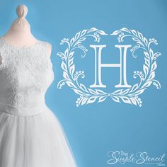 a white dress on a mannequin next to a blue background with the letter h