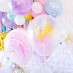 some balloons and confetti on a white table with pink, blue, yellow and purple colors