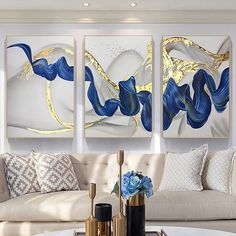 three paintings are hanging on the wall above a coffee table in a modern living room