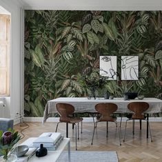 a dining room with a table and chairs in front of a wallpapered background