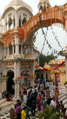 many people are standing in front of an ornate building with orange and yellow decorations on it