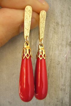 a pair of red earrings with gold accents