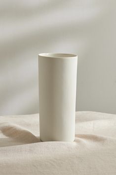 a white cup sitting on top of a bed