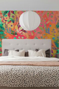 a large bed sitting in front of a colorful wall