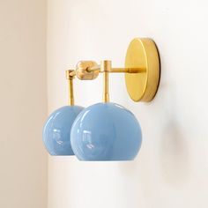 two blue balls are attached to the wall by brass fittings and one light is on