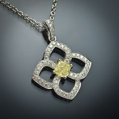 The soft design of this flower-shaped pendant features .38 carats of G VS2 round brilliant white diamonds and a .52 carat GIA-certified cusion-cut yellow diamond. The pendant is set in 18K white gold and delicately floats on a 16 inch 18K white gold cable chain.