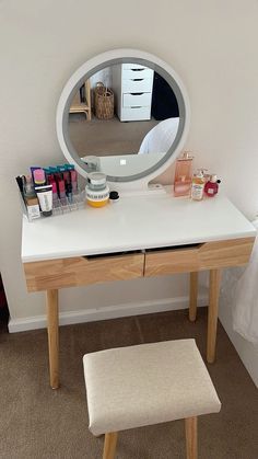 there is a mirror on the wall next to a desk with makeup and other items