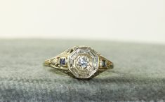 These early filigree rings are so pretty.  This is a Edwardian filigree band in 14KW gold with a 0.23CT Diamond and  side synthetic Sapphires.  Synthetic colored stones were common in the Edwardian era. This ring weighs 2.8 grams in size 5.5 and could be sized by your local jeweler. Antique Diamond Rings With Accent Stones, Antique White Diamond Filigree Ring, Antique Silver Sapphire Ring With Diamond Accents, Fine Jewelry Diamond Ring With Filigree In Round Cut, Fine Jewelry Diamond Ring With Filigree, Art Deco Sapphire Ring With Accent Stones, Art Deco Yellow Gold Diamond Ring With Intricate Design, 14k Gold Silver Filigree Ring With Diamond Cut, Silver 14k Gold Filigree Ring With Intricate Design