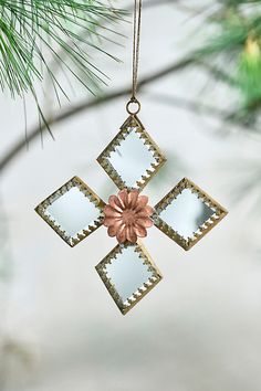 an ornament hanging from a christmas tree with a flower in front of it