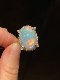 Stunning oval opal cabochon weighing 10.6 carats of mesmerizing hot pinks, red, orange and neon hues. The opal is 10 mm in depth/height is held by 4 tall prongs with bezel accented with 36 dainty diamonds. A larger round faceted cut diamond is placed at the base of each prong. Slim simple 14k solid yellow gold band for comfortable wear. Gorgeous timeless piece of jewelry!  Stone: Ethiopian opal, diamonds Stone weight: 10.6 carats Stone size: 18 x 12 mm  Stone shape: sphere Metal: 14K yellow gold Metal weight: 4.32 grams We gladly accept custom orders using either our designs or design of your choice with stones from our collection or your own.  Please contact us directly for details.  Please feel free to visit my shop for additional pieces of high end natural gemstone jewelry: https://www. Elegant Ethiopian Opal Ring With Oval Cabochon, Yellow Gold Ethiopian Opal Ring In Oval Cabochon Shape, Gold Ethiopian Opal Cabochon Ring, Unique Ethiopian Opal Cabochon Rings, Large Engagement Rings, Elegant Ethiopian Opal Ring, Oval Cabochon, Opal Band, Ethiopian Opal Ring, Rainbow Opal