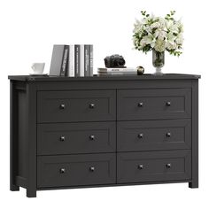 a black dresser with white flowers and books on it's top, against a white background