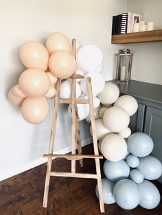 a ladder with balloons on it in front of a white wall and wood flooring