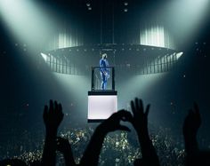 a man standing on top of a white box in front of a crowd at a concert