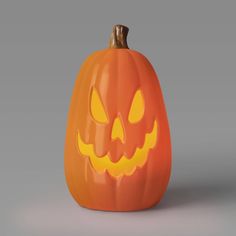 an orange carved pumpkin with glowing eyes on it's face and mouth, sitting in front of a gray background