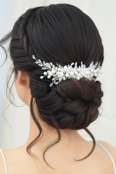 Elegant low bun with side braiding and decorative floral hair accessories adds a touch of classic sophistication to any special occasion. Shiny black hair provides the perfect canvas for this refined updo. Perfectly placed tendrils frame the face for a soft, romantic finish.  // Photo Credit: Instagram @nissara_hairstylist_thailand Low Wedding Bun Hairstyles, Bride Hairstyles For Black Hair, Braid Low Bun Wedding Hair, Dark Hair Low Bun Wedding, Wedding Simple Updo Brides, Wedding Hair Updo Classic, Bridal Cornrow Hairstyles, Bridal Bun With Hair Piece, Low Bun Wedding Hair Asian