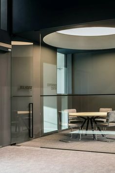 an office meeting room with glass walls and round conference table in the center surrounded by chairs