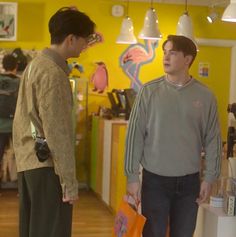 two young men standing in a store looking at each other's handbages